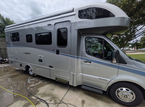 Class C motorhome being washed on a driveway
